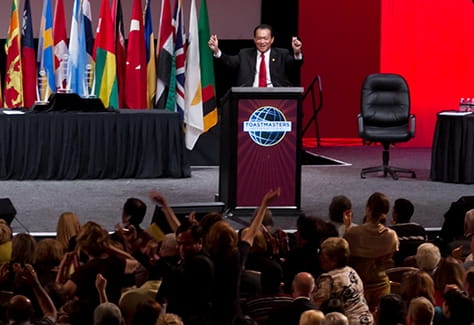 Toastmaster behind a lectern is receiving applause from the audience